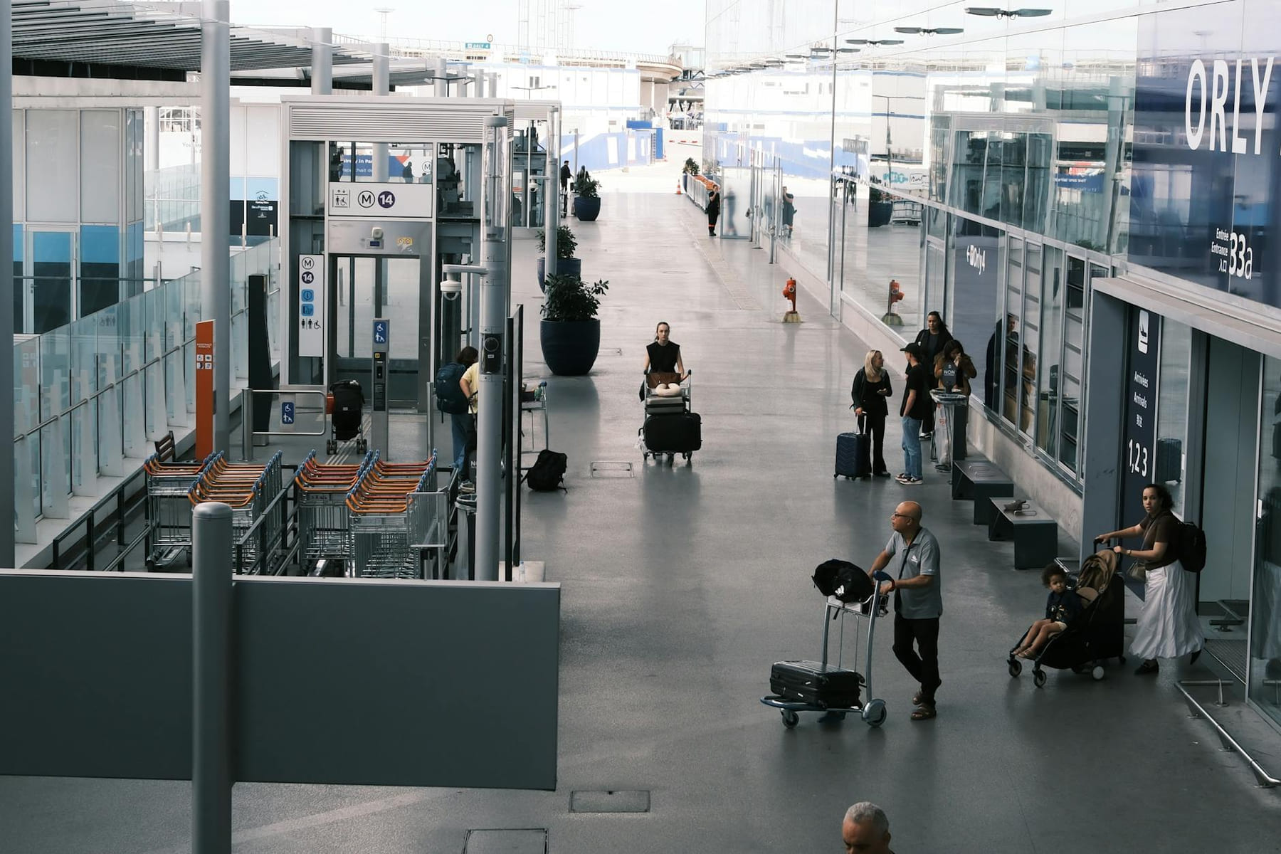 Travelers navigate an airport terminal corridor with luggage carts and suitcases. on Miles and Memories