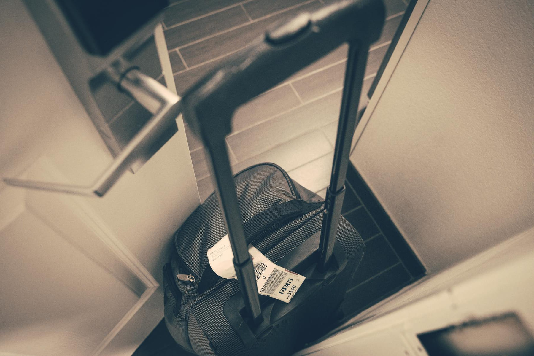 Travel suitcase with tag by hotel door, symbolizing travel or business trip. on Miles and Memories