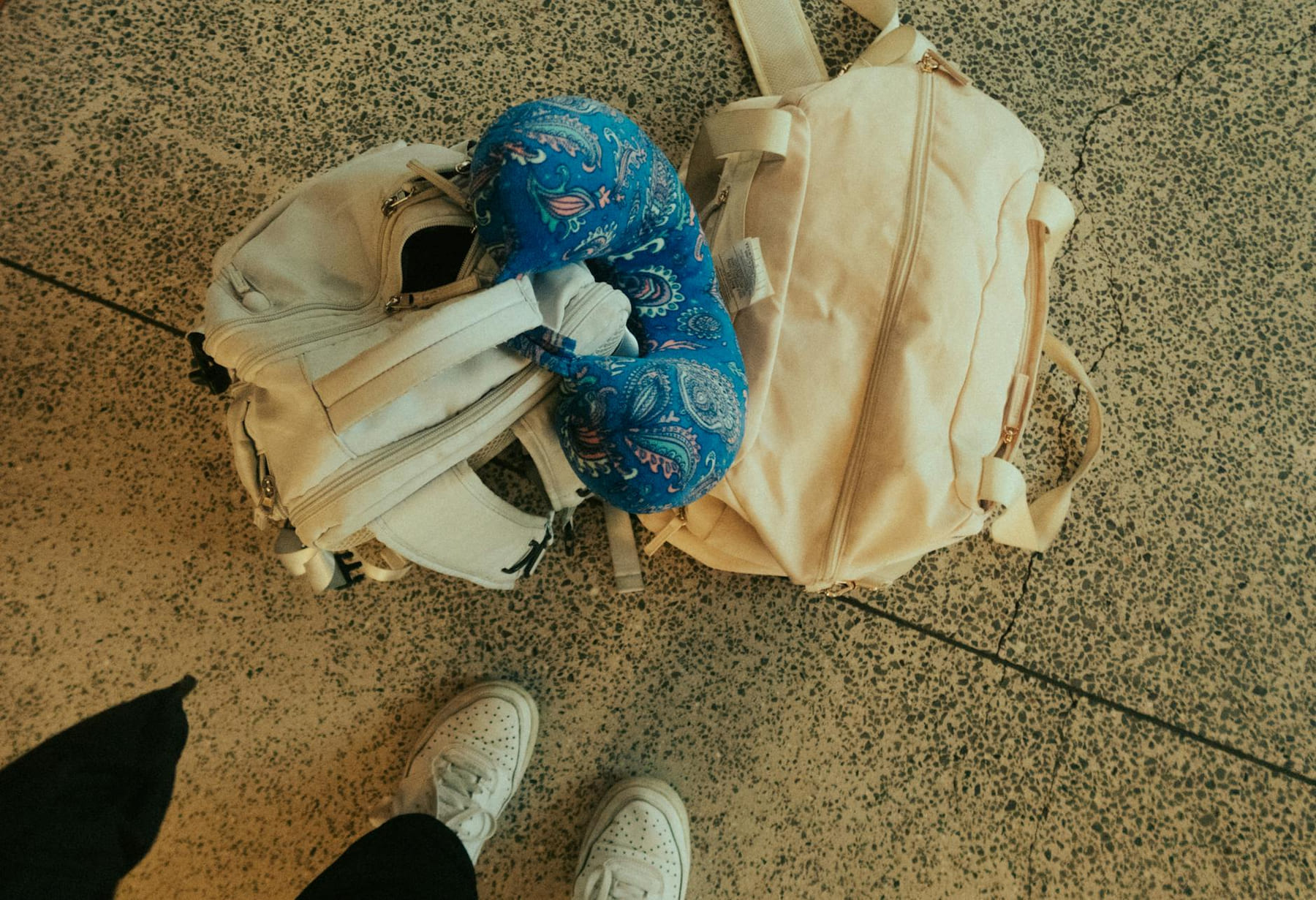 Top view of luggage, backpack, and neck pillow at airport, ready for travel. on Miles and Memories