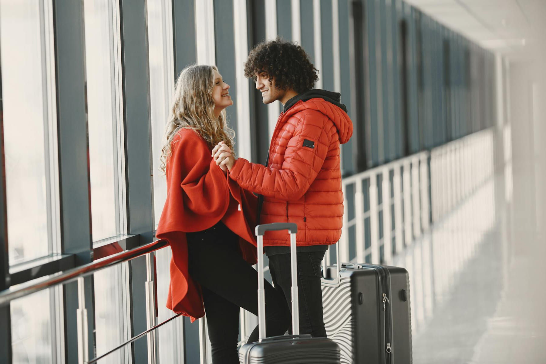 A cheerful couple holding hands with luggage in an airport terminal, ready for travel. on Miles and Memories