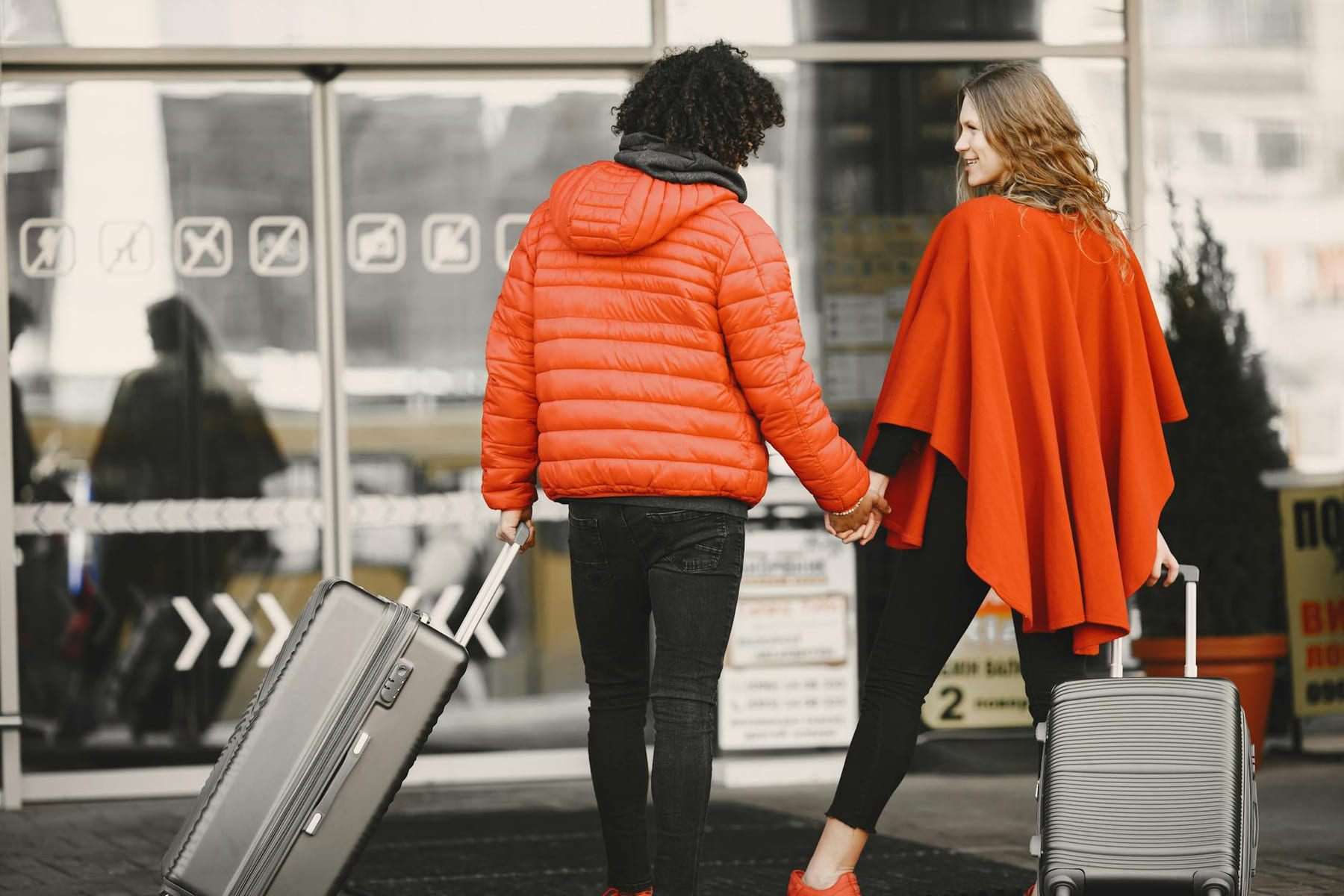 A couple holding hands with luggage, entering an airport for a travel journey. on Miles and Memories