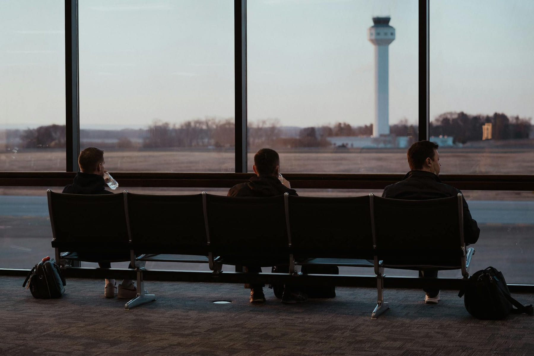 People sitting in airport terminal, watching runway scenes through large windows. on Miles and Memories