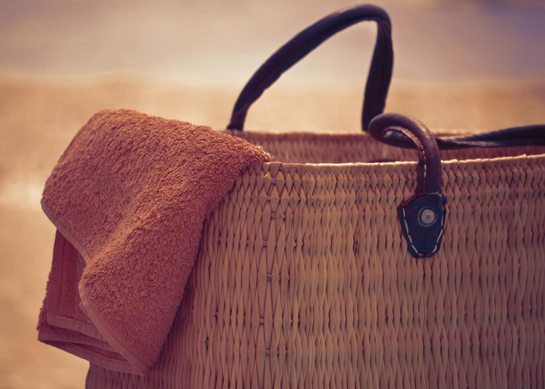 A straw beach bag with a towel draped over it, perfect for a summer day at the shore. on Miles and Memories