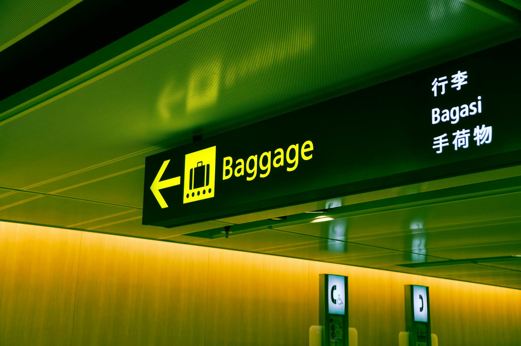 Illuminated airport baggage sign with multilingual translations pointing direction for travelers. on Miles and Memories