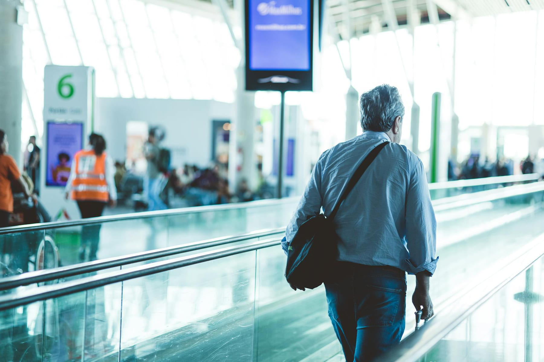 An adult male walking on an airport travelator, captured in a modern and well-lit terminal. on Miles and Memories