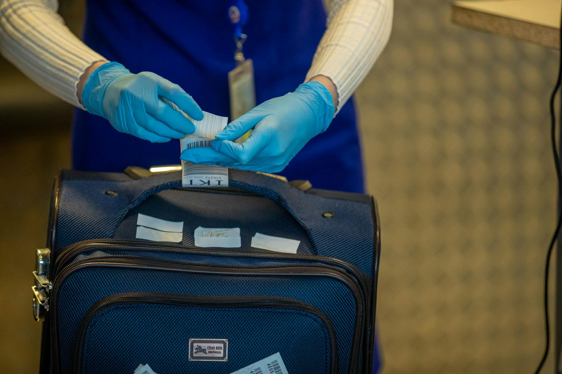 Close-up of airport security process with gloved hands inspecting luggage tags. on Miles and Memories