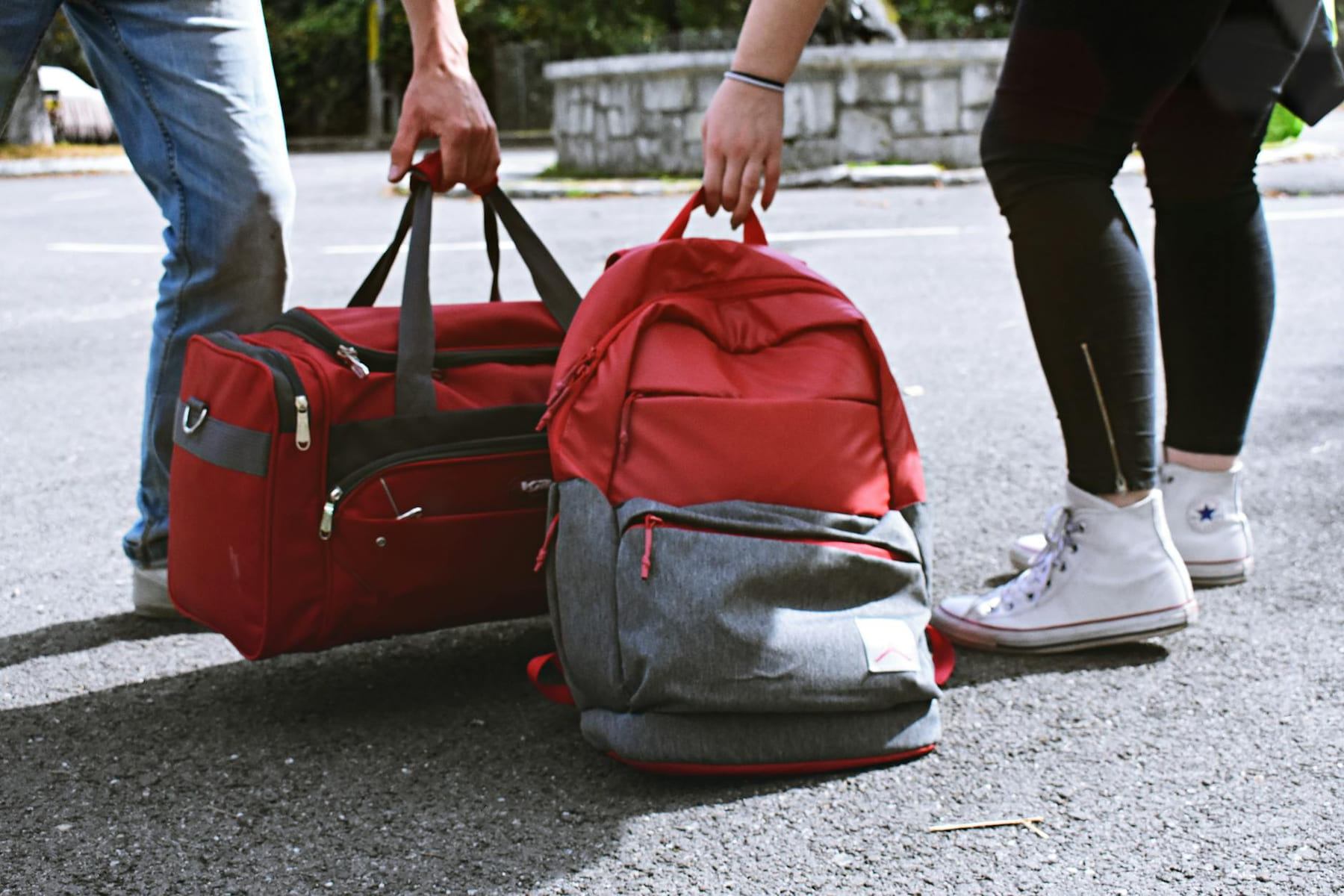 Two travelers holding red bags on a street, symbolizing travel and exploration. on Miles and Memories