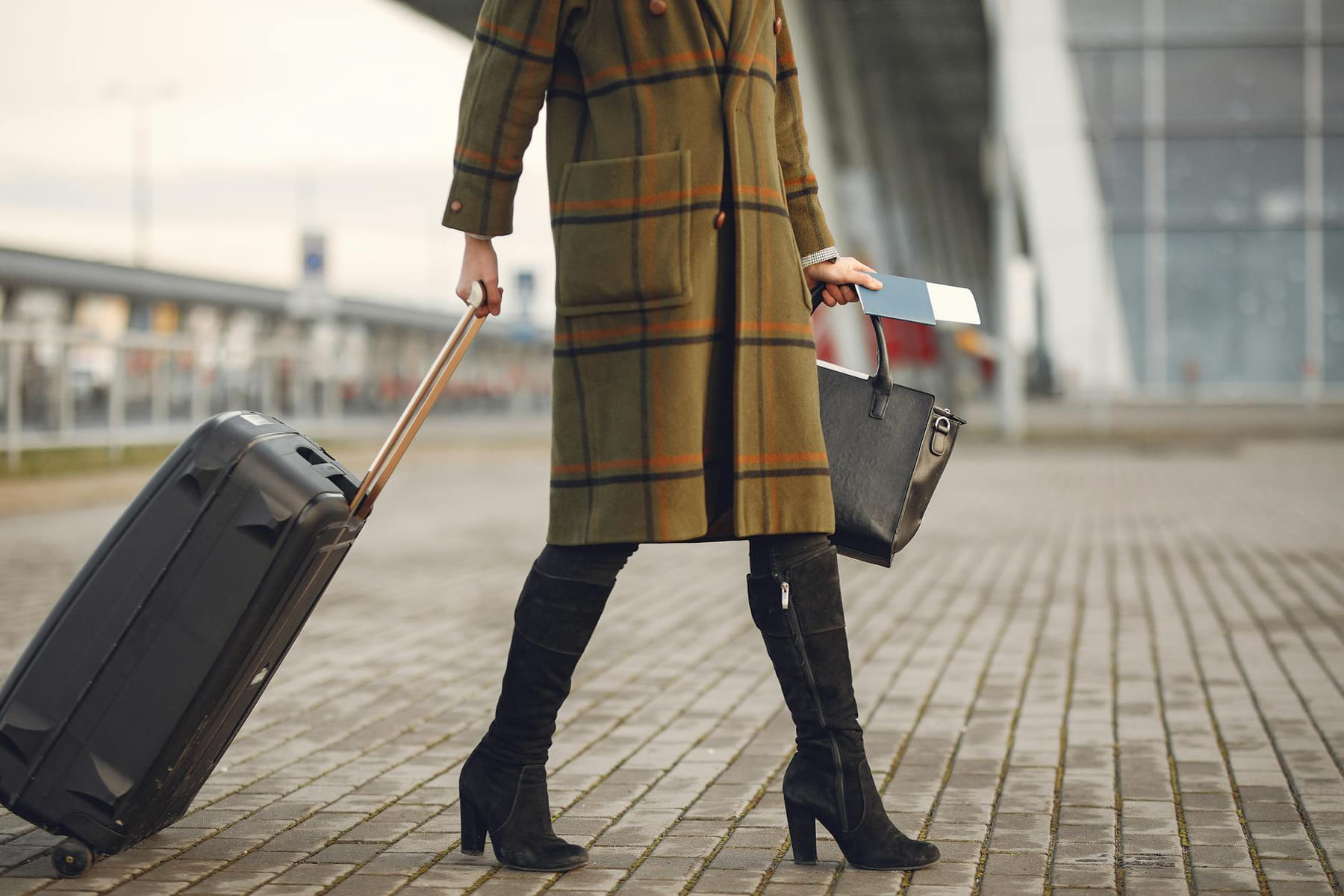 Stylish woman pulls suitcase at airport, ready for travel. on Miles and Memories